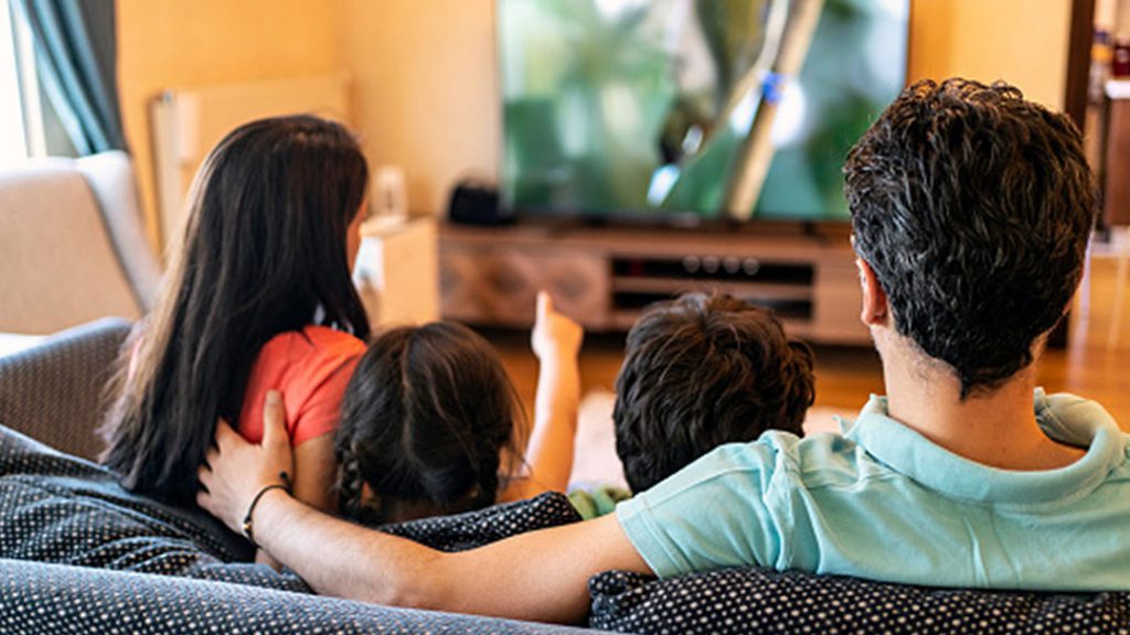 Four family members sitting on the couch and watching television