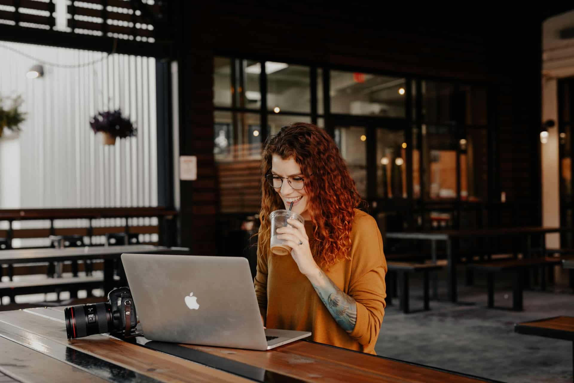 Happy woman at her computer sipping a drink