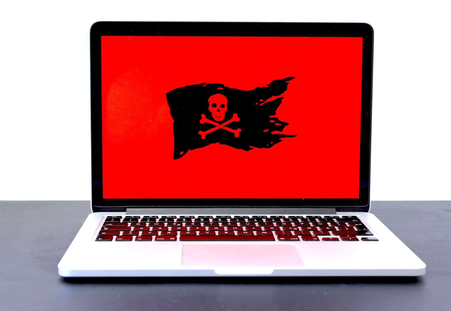 Laptop with a red background with a black pirate flag