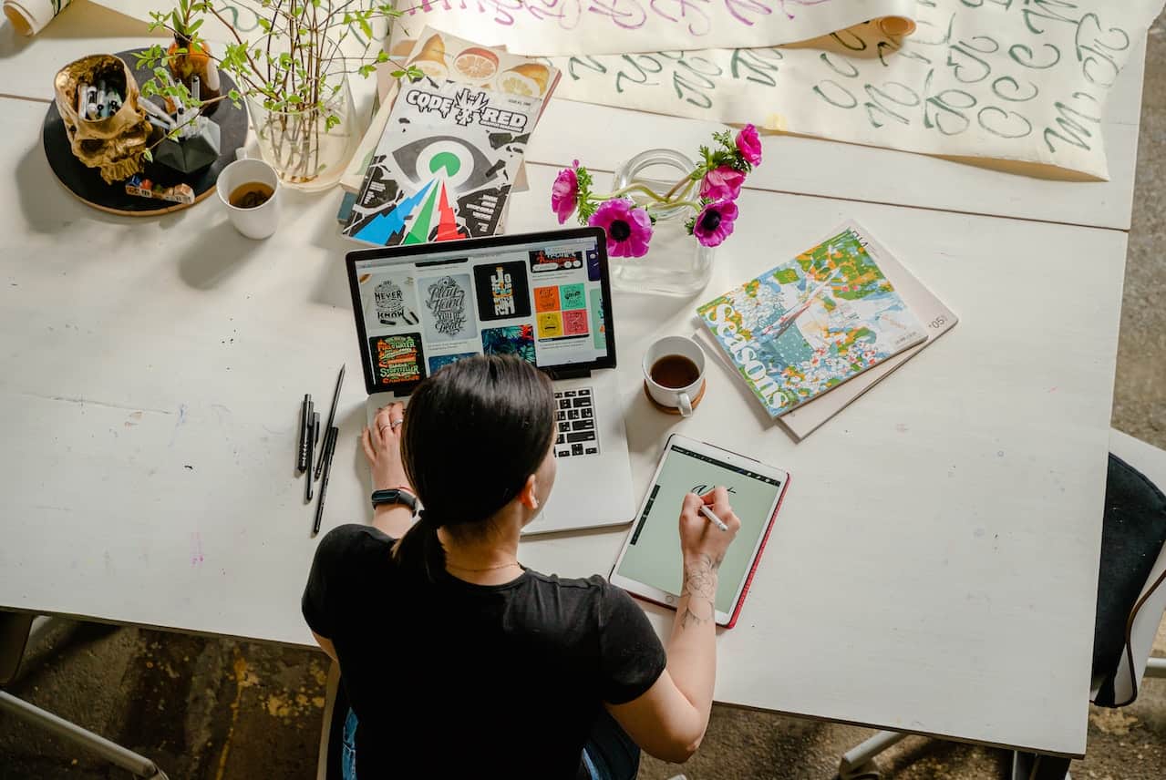 Woman drawing on a table in front of her laptop