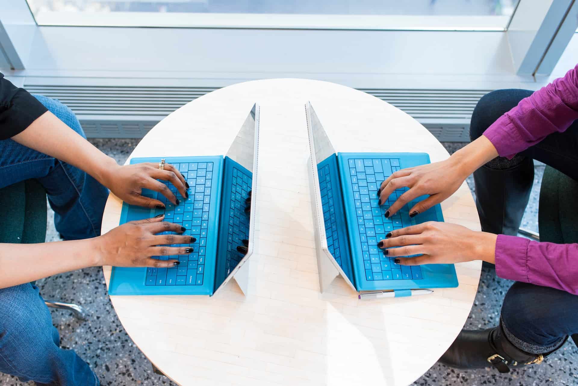 Two people working on laptops together